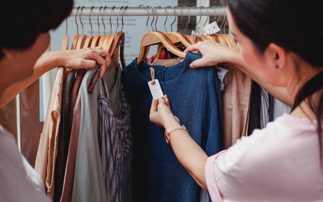 two people looking at price tags on clothes to make money through strategic shopping