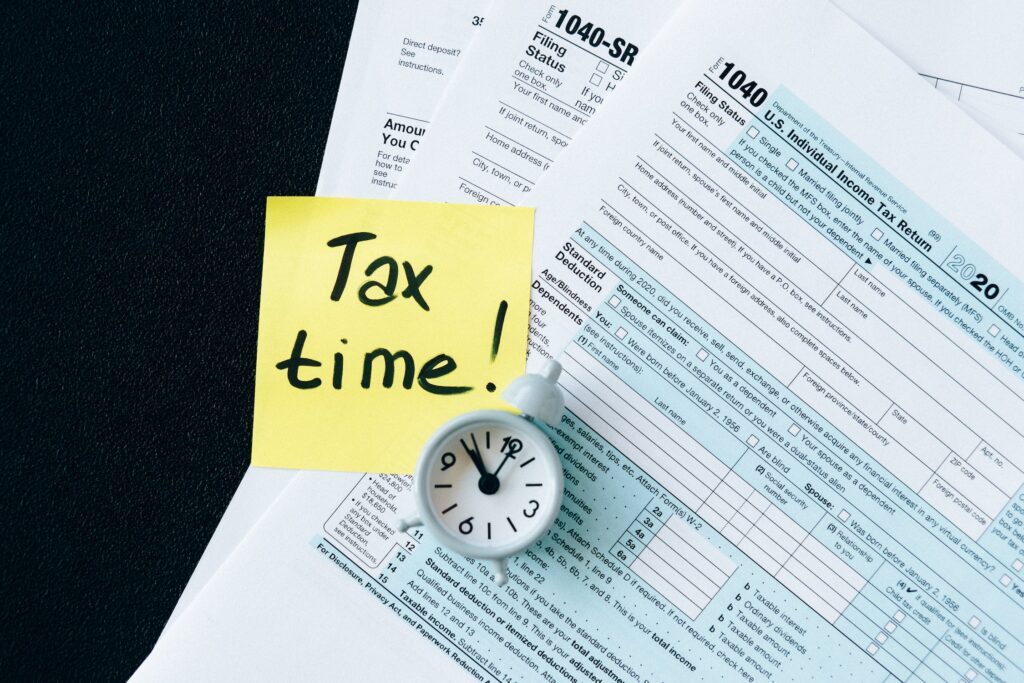 Sticky note with "tax time" written on it on top of tax forms