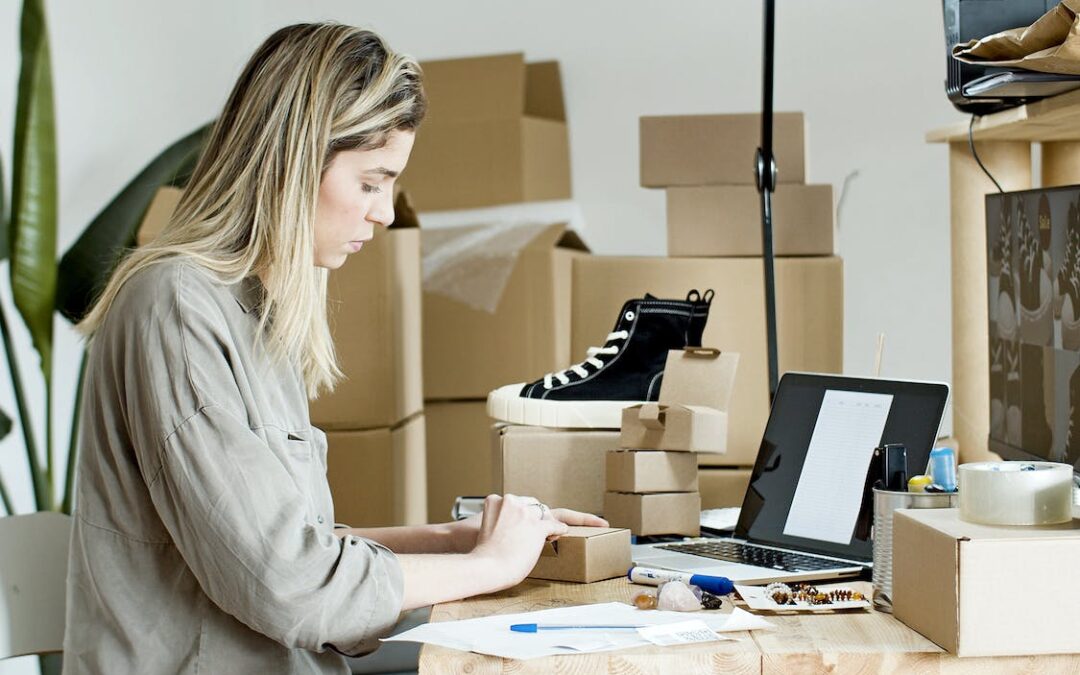 A woman with a laptop sitting next to boxes