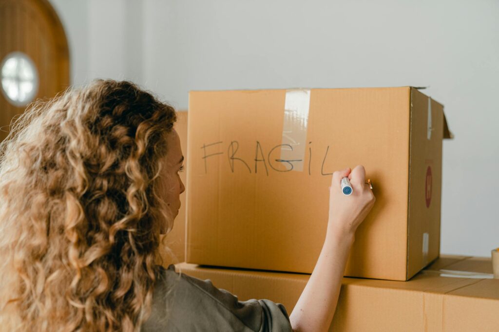 A woman writing on a cardboard box