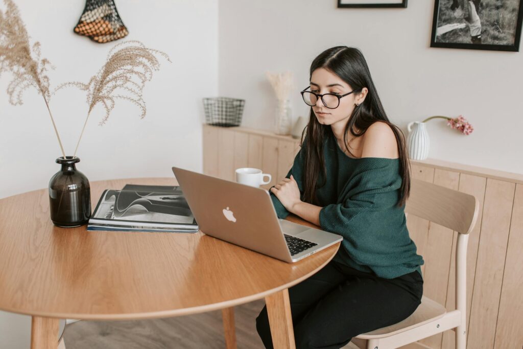 Woman looking at her laptop next to a coffee mug